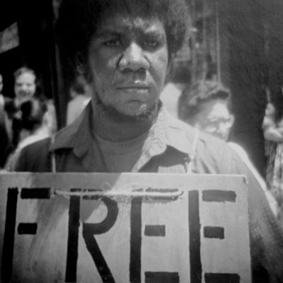 young black man parading crude sandwich-board in midtown Manhattan on a hot day in 1983